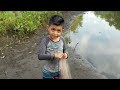 niño pesca en el río con atarralla y mira lo que agarro